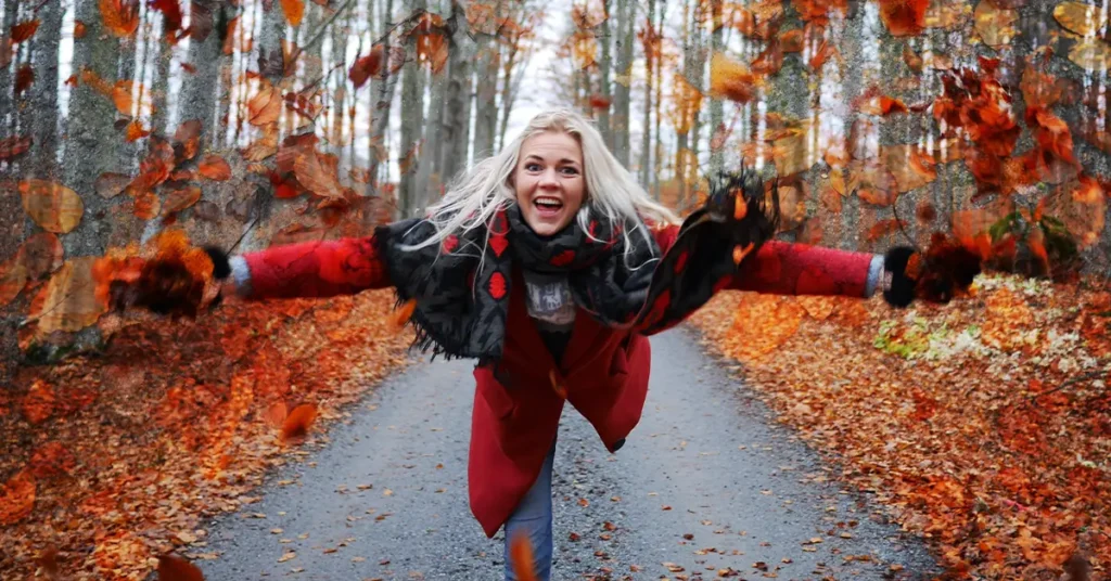 Portrait of smiling woman running in forest during autumn