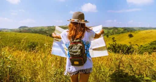 Rear view of woman with map standing on field against sky