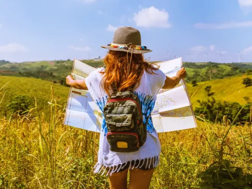 Rear view of woman with map standing on field against sky